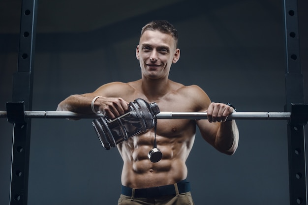 Acqua potabile dell'uomo caucasico di forma fisica dopo l'allenamento in palestra.