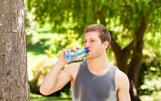 Acqua potabile dell&#39;uomo sportivo nel parco