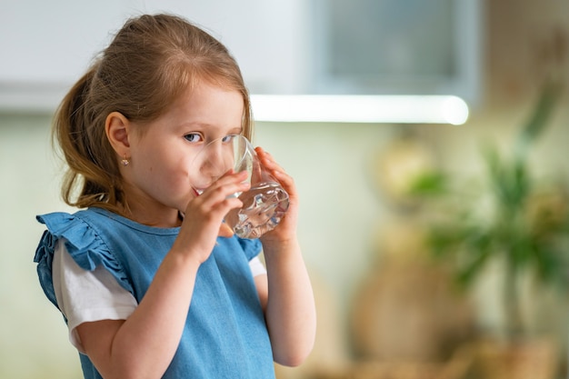 Acqua potabile della bambina sveglia in cucina a casa