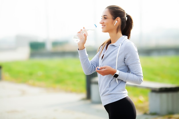 Acqua potabile della bella donna ed ascoltare la musica dopo avere corso