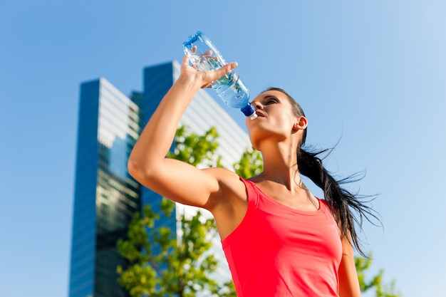 Acqua potabile della donna atletica in un ambiente urbano