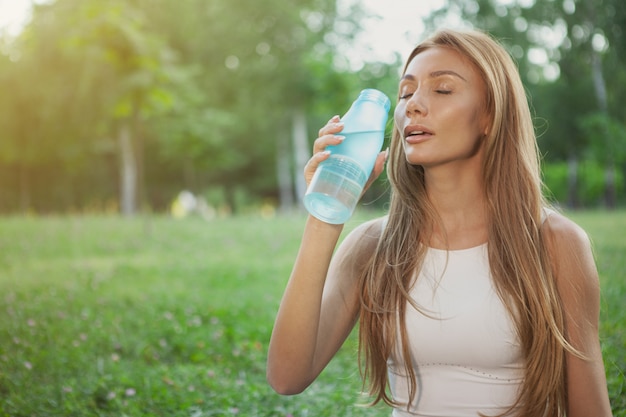 Acqua potabile della donna atletica splendida al parco