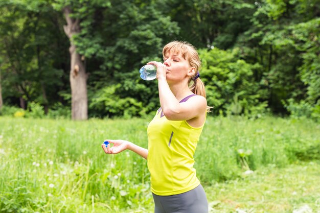 Acqua potabile della donna di forma fisica dalla bottiglia.