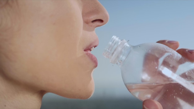 Acqua potabile della donna dopo la formazione di yoga all'aperto Ragazza che riposa dopo l'allenamento