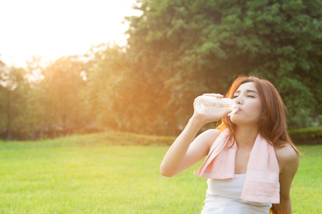 Acqua potabile della donna e sedersi sull&#39;erba.