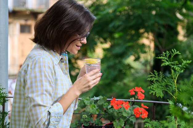 Acqua potabile della donna matura con il limone. Antiossidante naturale, bevanda dietetica, salute, prima bevanda mattutina, spazio copia