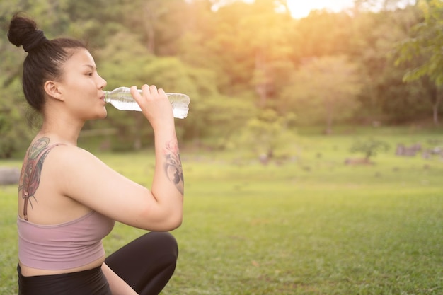 Acqua potabile della giovane bella donna dopo l'esercitazione nel parco