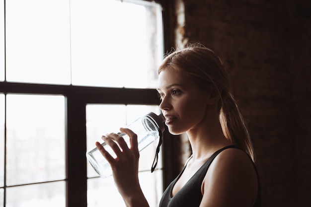 Acqua potabile della giovane donna attraente di forma fisica.