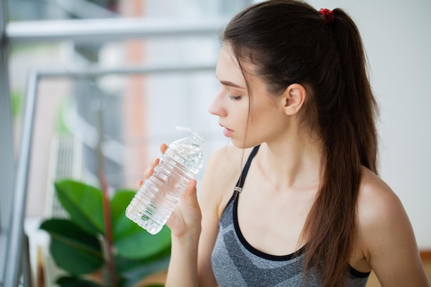 Acqua potabile della giovane donna bella ragazza che tiene una bottiglia d'acqua