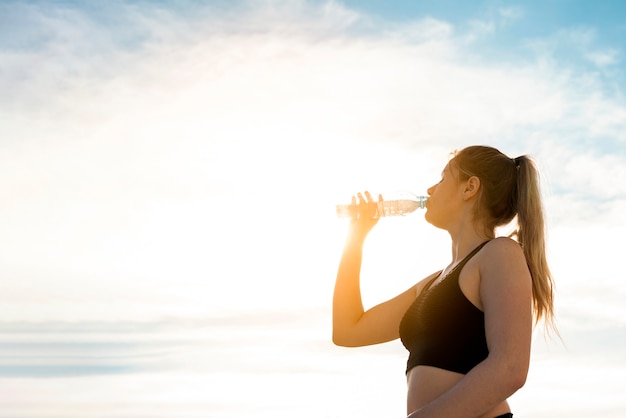 Acqua potabile della giovane donna da una bottiglia