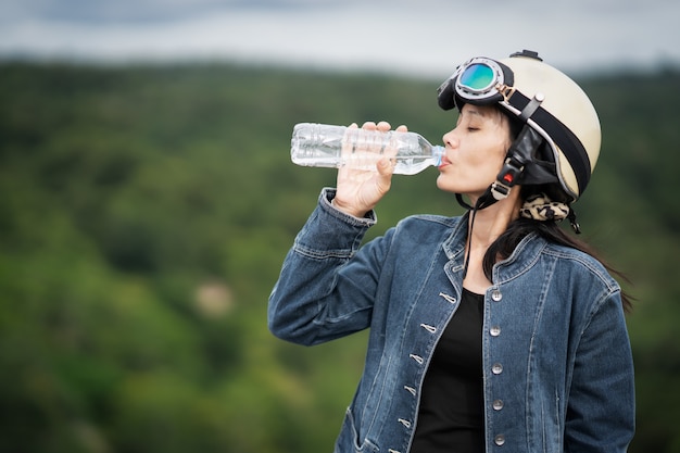 Acqua potabile della ragazza sveglia da rinfrescare sul bello fondo vago della natura della foresta verde