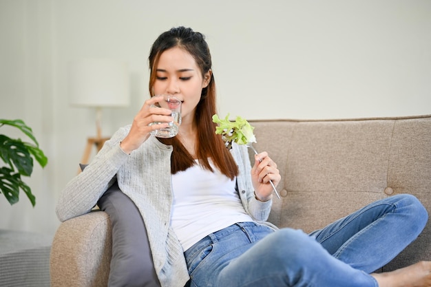 Acqua potabile femminile asiatica rilassata e sana e che mangia la sua insalata sana