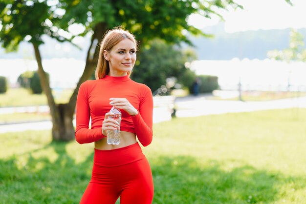 Acqua potabile sottile della giovane donna dopo l'allenamento