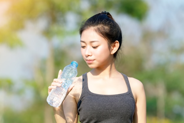 Acqua potabile sportiva dell&#39;Asia della donna all&#39;aperto il giorno soleggiato