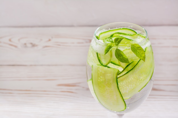 Acqua rinfrescante con fette di cetriolo e foglie di basilico in un bicchiere