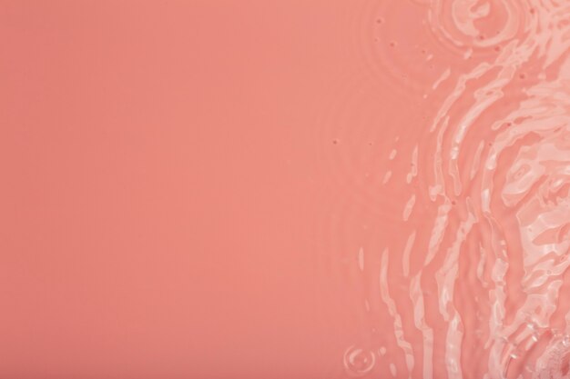 Acqua tranquilla ripple sfondo cerchi e bolle di struttura dell'acqua su un cosmetico di superficie rosa liquido...