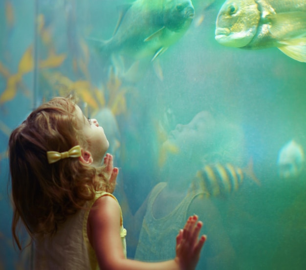 Acquario ragazza e bambino che guarda il pesce per imparare la curiosità e lo sviluppo della conoscenza e la natura Educazione acquario e bambino che guarda la vita marina o gli animali nuotano sott'acqua nell'oceanario