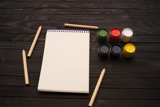 Acquerelli, vernici, matite, blocchi di appunti, strumenti di disegno, arte, sfondo in legno scuro, foto di alta qualità