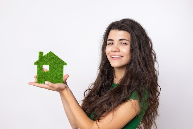 Acquirente di casa felice Una giovane ragazza tiene in mano un modello di una casa verde Il concetto di ecologia dell'energia verde