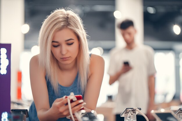 Acquisto di un nuovo smartphone presso il negozio di tecnologia. Alla ricerca di un nuovo gadget tecnologico per la pace. Bella donna nello shopping.