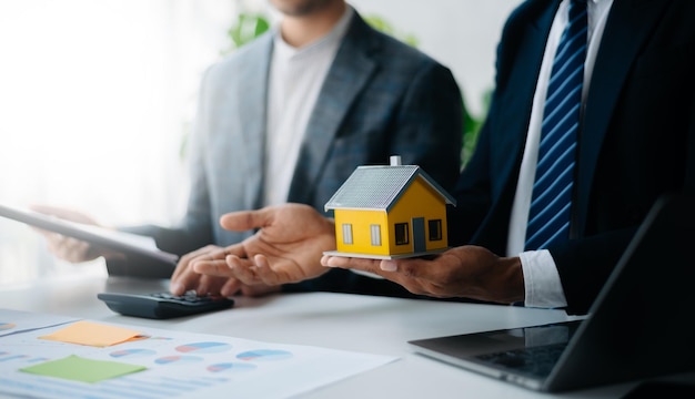 Acquisto di una casa o contratto di assicurazione un agente assicurativo che punta la penna a chi è interessato ad affittare una casa un contratto firma di un contratto di acquisto di una casa