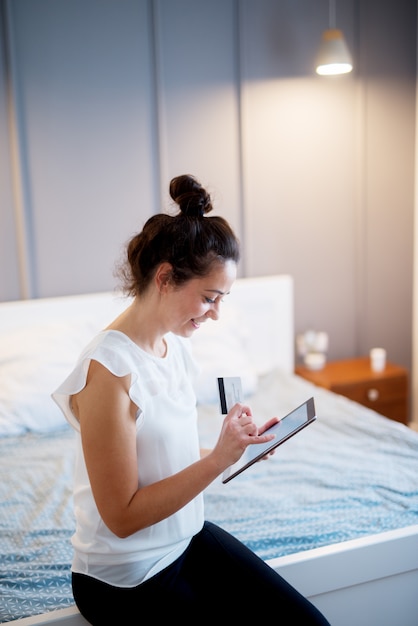 Acquisto invecchiato centrale della donna sulla compressa alla camera da letto.