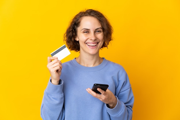 Acquisto isolato della giovane donna con il cellulare con una carta di credito