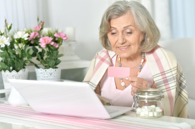 Acquisto senior della donna con il computer portatile