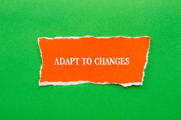 Adattarsi ai cambiamenti Lettere su un pezzo di carta arancione strappato con sfondo verde Foto concettuale