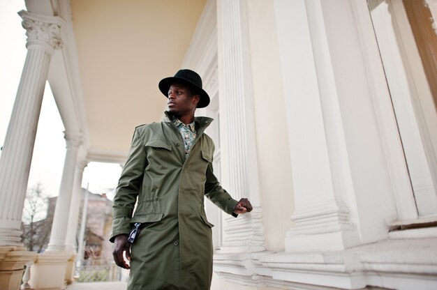 Adatti il ritratto dell'uomo afroamericano nero sul mantello del cappotto verde e black hat, palazzo giallo del fondo