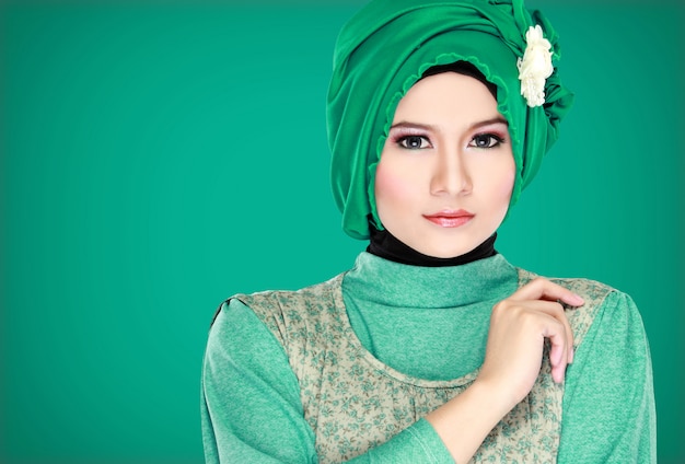 Adatti il ritratto di giovane bella donna musulmana con il costume verde che indossa l'hijab