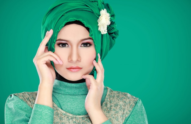 Adatti il ritratto di giovane bella donna musulmana con il costume verde che indossa l'hijab