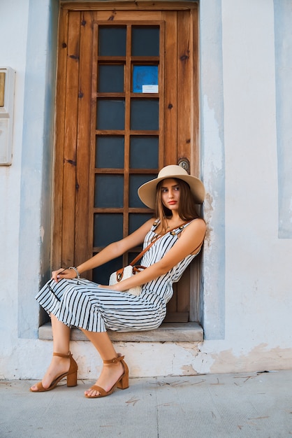 Adatti il ritratto di giovane donna alla moda che cammina sulla via.