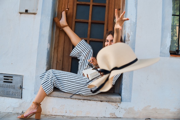 Adatti il ritratto di giovane donna alla moda che posa sulla via.