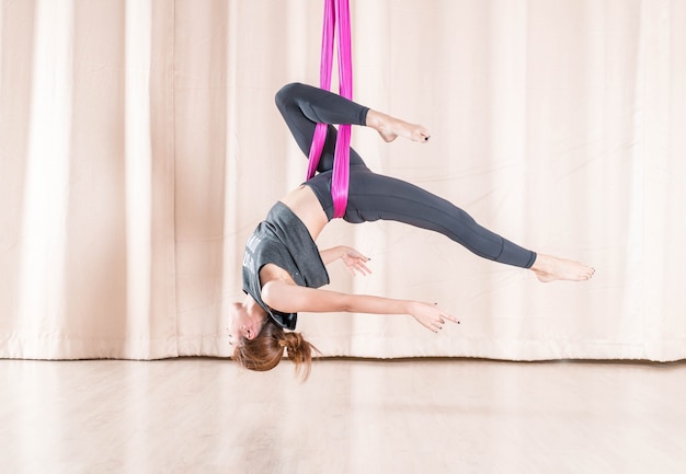 Addestramento asiatico della donna nella stanza di forma fisica con gli elementi di yoga della mosca