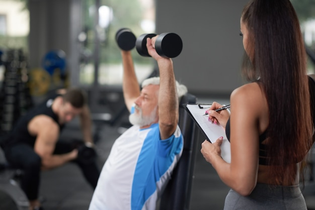 Addestramento dell'uomo più anziano con la donna in palestra.