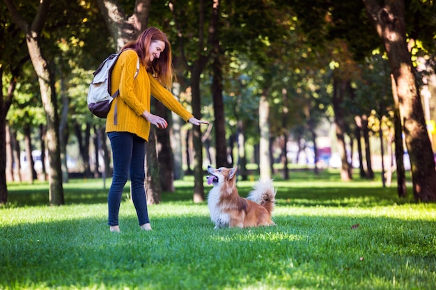 Addestramento - ragazza e cane corgi che camminano nel parco