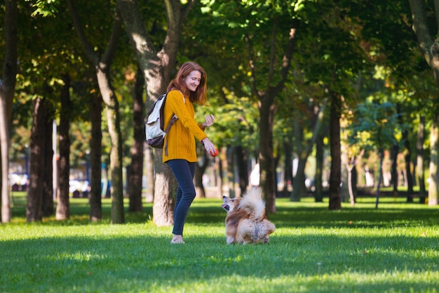 Addestramento - ragazza e cane corgi che camminano nel parco