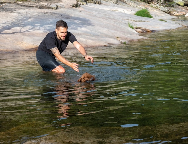 Addestratore di cani che insegna al cucciolo lanoso a nuotare in una laguna. Cucciolo marrone che impara a nuotare in un lago.