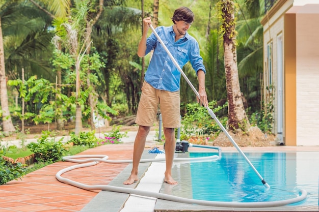 Addetto alle pulizie della piscina uomo in camicia blu con attrezzatura per la pulizia delle piscine soleggiate