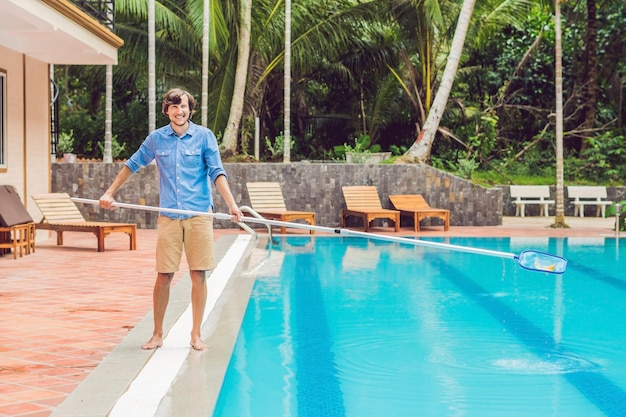 Addetto alle pulizie della piscina uomo in camicia blu con attrezzatura per la pulizia delle piscine soleggiate