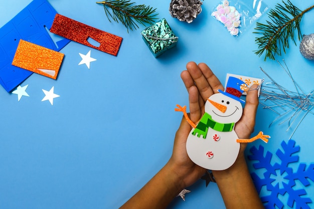 Addobbi da appendere all'albero di Natale. Parti del pupazzo di neve su fondo di legno blu. Idee per lavoretti di Natale. Vista dall'alto. Avvicinamento. FAI DA TE.