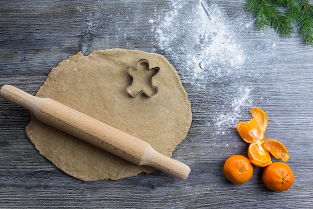 Addobbi di Capodanno e Natale su una superficie di legno con mandarini e un albero di Natale Preparare e stendere la pasta per la cottura del pan di zenzero