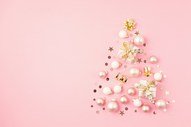 Addobbi natalizi e confezioni regalo disposte a forma di albero di Natale sulla superficie rosa