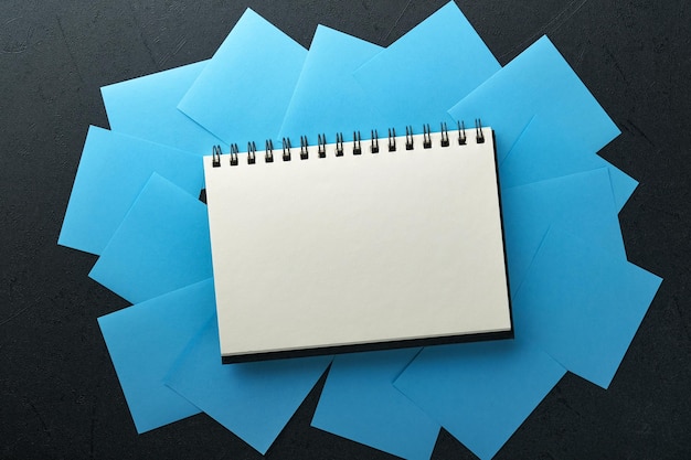 Adesivi di carta blu e blocco note o libro al centro su sfondo nero Note adesive vuote con spazio di copia pronto per il tuo messaggio Concetto di obiettivi o risoluzioni per il nuovo anno Idea del lunedì blu Mock up