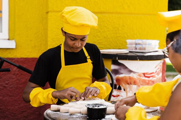Adolescente africano nero cuoco con cappello da chef e grembiule giallo pasta da cucina uniforme per prodotti da forno Pubblicità creativa per bar o ristorante
