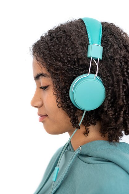 Adolescente afroamericano con capelli ricci, guardando in basso e ascoltando musica in moderne cuffie turchesi