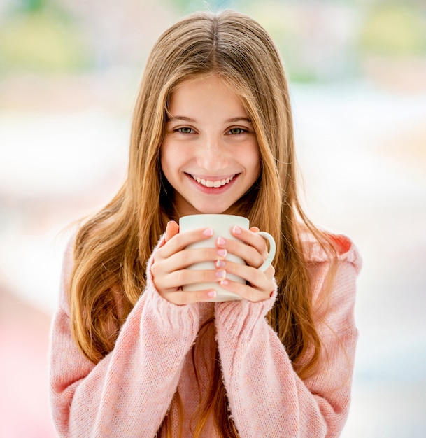 Adolescente allegro che tiene tazza bianca