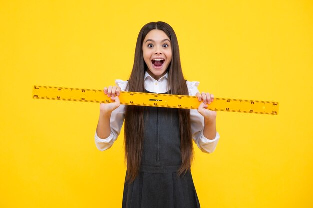 Adolescente bambino scuola ragazza azienda misura per la lezione di geometria Misurazione dell'altezza Apparecchiature di misurazione Matematica di studio dello studente del capretto Eccitato viso emozioni allegre della ragazza adolescente