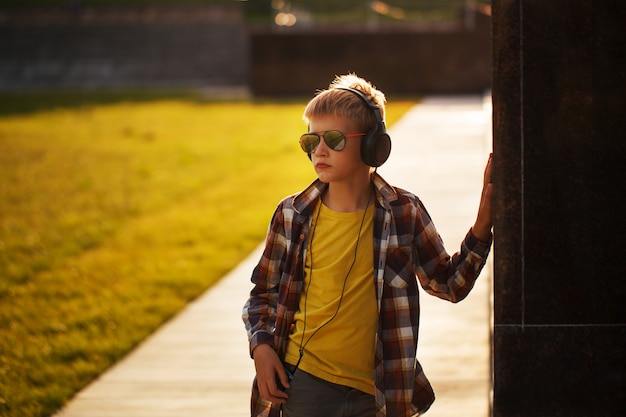 Adolescente bello che ascolta la musica e che per mezzo del telefono sul tramonto